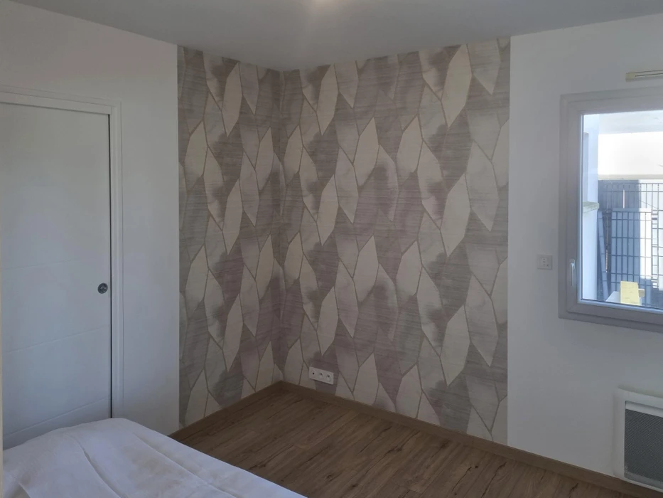 Intérieur résidentiel moderne avec mur d'accent décoratif. Une personne applique un revêtement texturé sur une surface murale blanche adjacente.