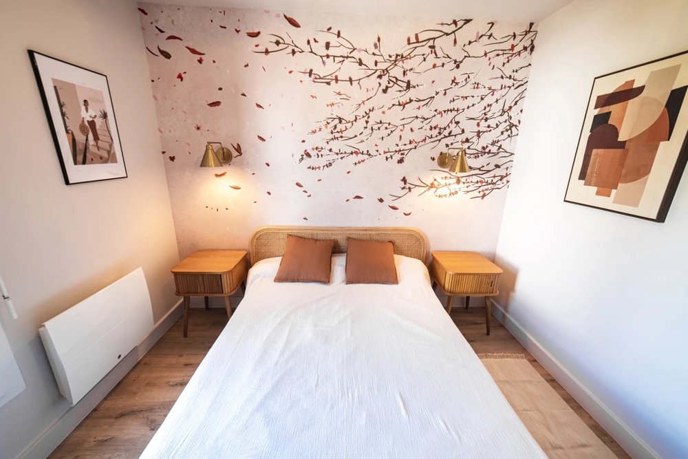 Chantier de rénovation intérieure en cours avec mur accent peint en terre cuite orange dans une pièce aux murs blancs. Prises électriques et interrupteurs noirs installés, câbles apparents en attente de finition. Sol protégé par bâche plastique.