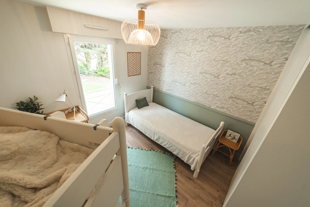 Chantier de rénovation intérieure en cours avec mur accent peint en terre cuite orange dans une pièce aux murs blancs. Prises électriques et interrupteurs noirs installés, câbles apparents en attente de finition. Sol protégé par bâche plastique.