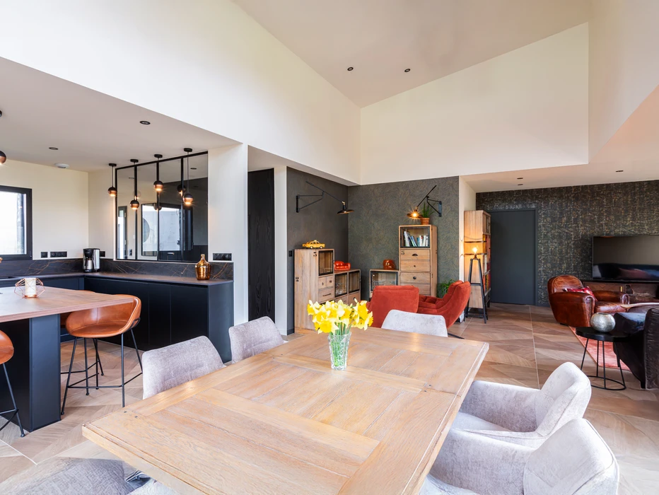 Chantier de rénovation intérieure en cours avec mur accent peint en terre cuite orange dans une pièce aux murs blancs. Prises électriques et interrupteurs noirs installés, câbles apparents en attente de finition. Sol protégé par bâche plastique.