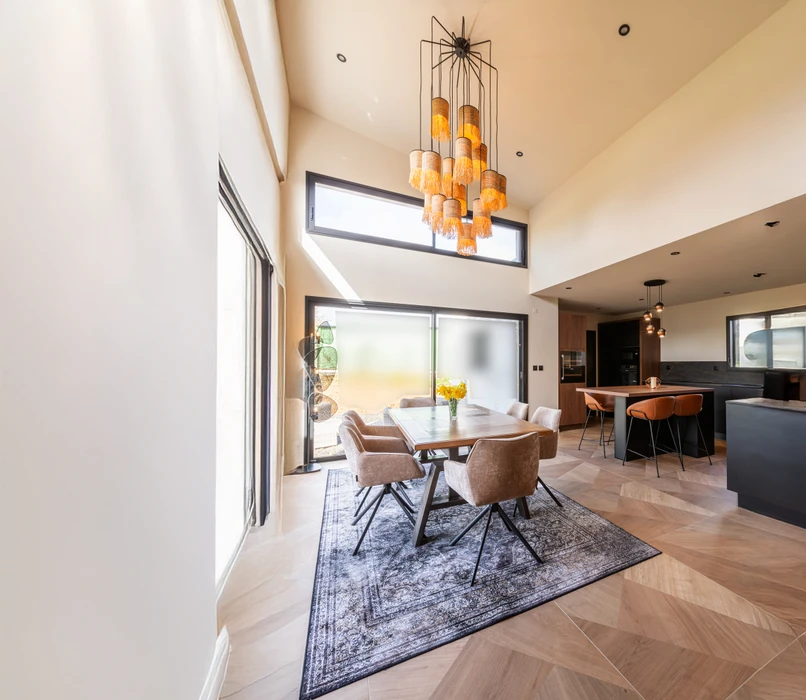 Intérieur résidentiel moderne avec mur d'accent orange terracotta contrastant avec murs blancs. Porte d'entrée sombre à gauche, grandes baies vitrées à cadre noir donnant sur l'extérieur à droite.