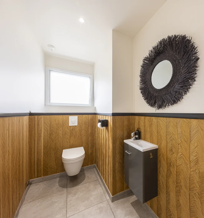 Chantier de rénovation intérieure en cours avec mur accent peint en terre cuite orange dans une pièce aux murs blancs. Prises électriques et interrupteurs noirs installés, câbles apparents en attente de finition. Sol protégé par bâche plastique.