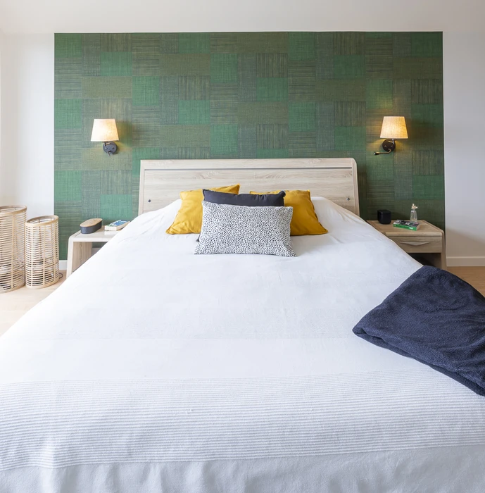 Chantier de rénovation intérieure en cours avec mur accent peint en terre cuite orange dans une pièce aux murs blancs. Prises électriques et interrupteurs noirs installés, câbles apparents en attente de finition. Sol protégé par bâche plastique.