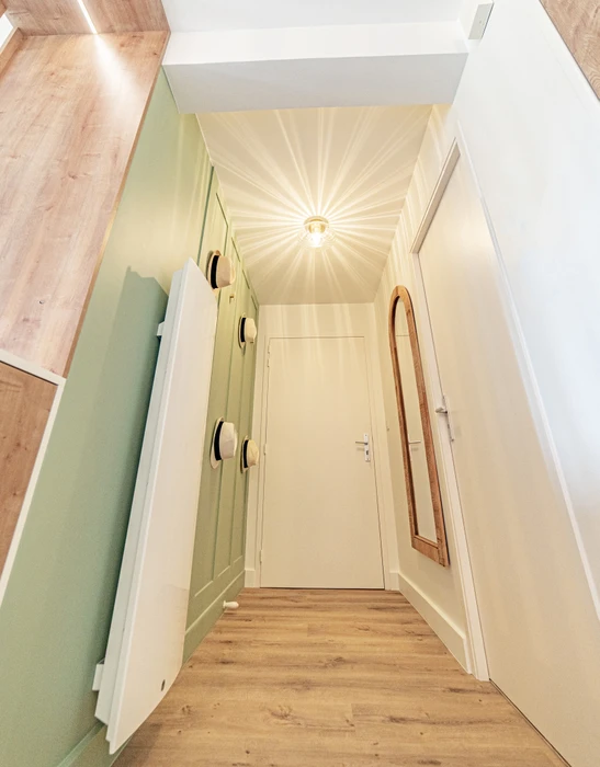 Intérieur d'une pièce en cours de finition avec mur accent peint en ocre jaune. Une personne travaille sur les finitions murales. Fenêtre avec encadrement noir sur mur blanc latéral.