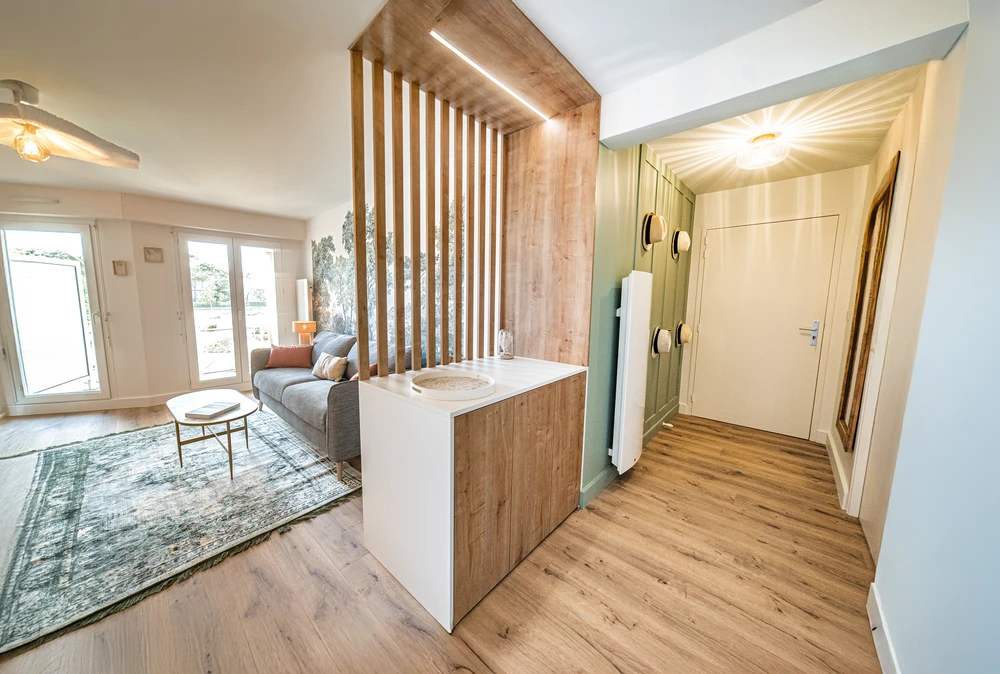 Chantier de rénovation intérieure en cours avec mur accent peint en terre cuite orange dans une pièce aux murs blancs. Prises électriques et interrupteurs noirs installés, câbles apparents en attente de finition. Sol protégé par bâche plastique.