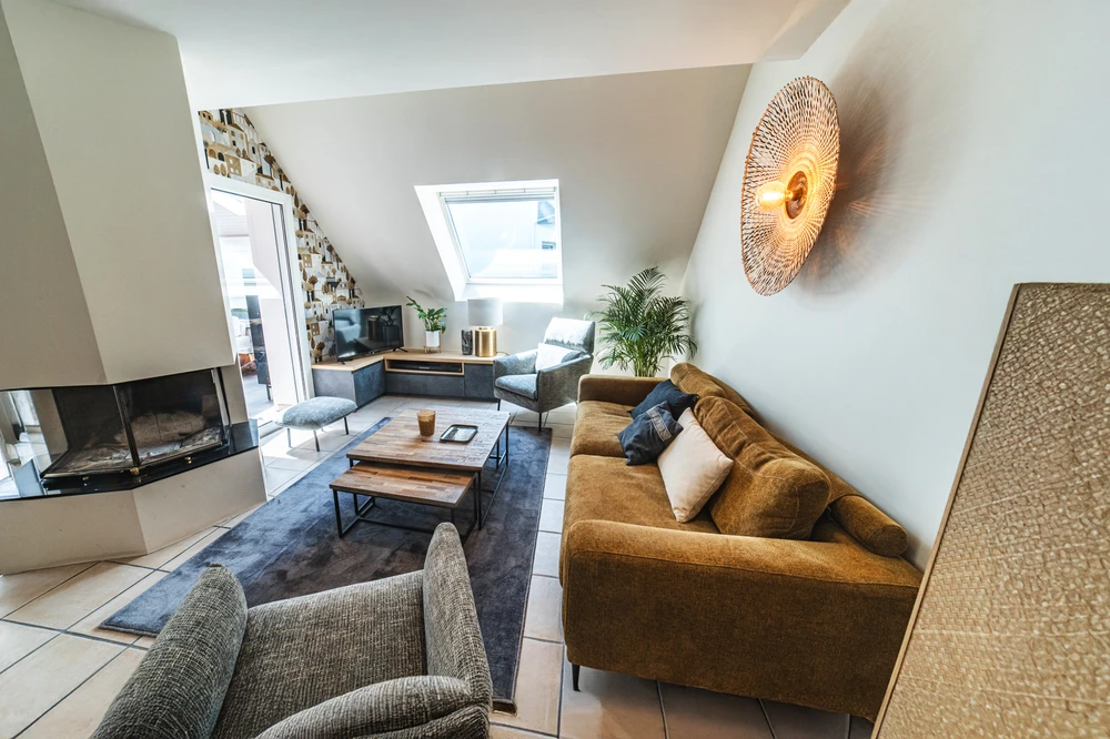 Chantier de rénovation intérieure en cours avec mur accent peint en terre cuite orange dans une pièce aux murs blancs. Prises électriques et interrupteurs noirs installés, câbles apparents en attente de finition. Sol protégé par bâche plastique.