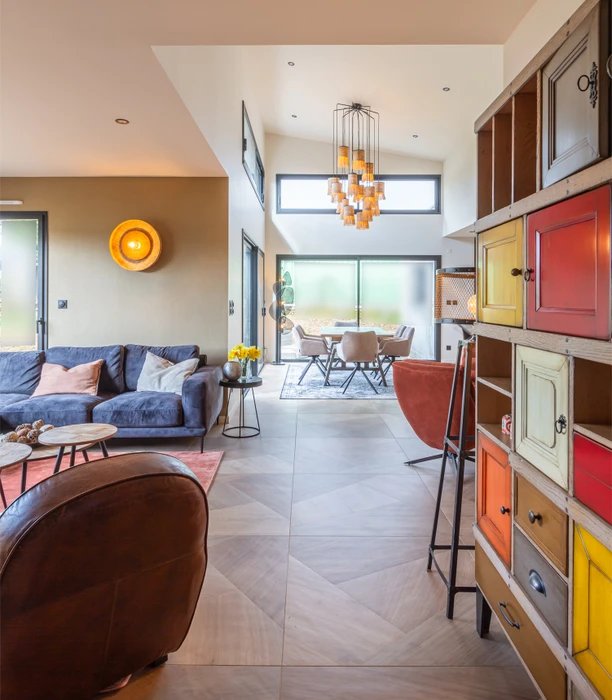Intérieur résidentiel moderne avec mur d'accent orange terracotta contrastant avec murs blancs. Porte d'entrée sombre à gauche, grandes baies vitrées à cadre noir donnant sur l'extérieur à droite.